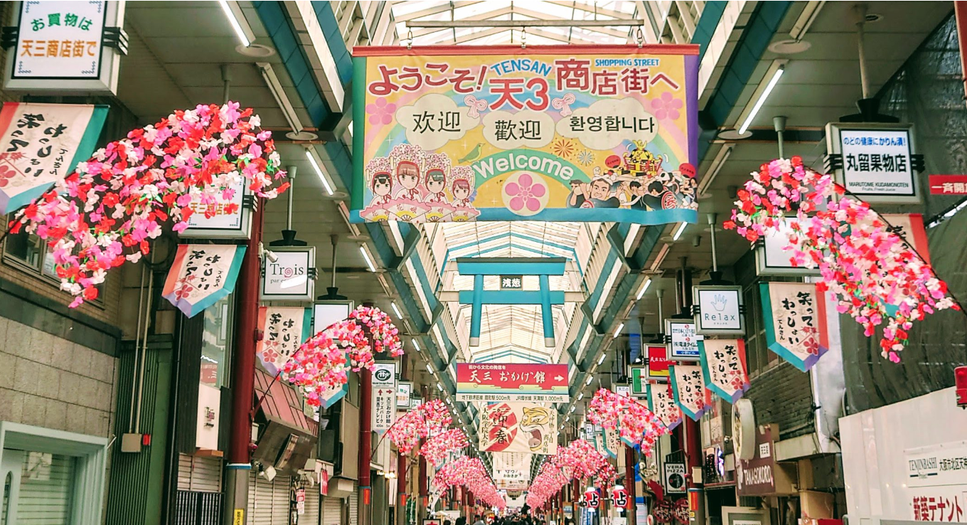Vibrant Tenjinbashi-suji shopping arcade in Osaka with banners and cherry blossom decor