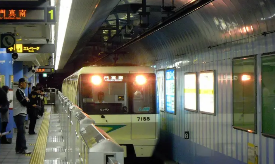 Osaka Metro train arriving at an underground station platform with passengers waiting