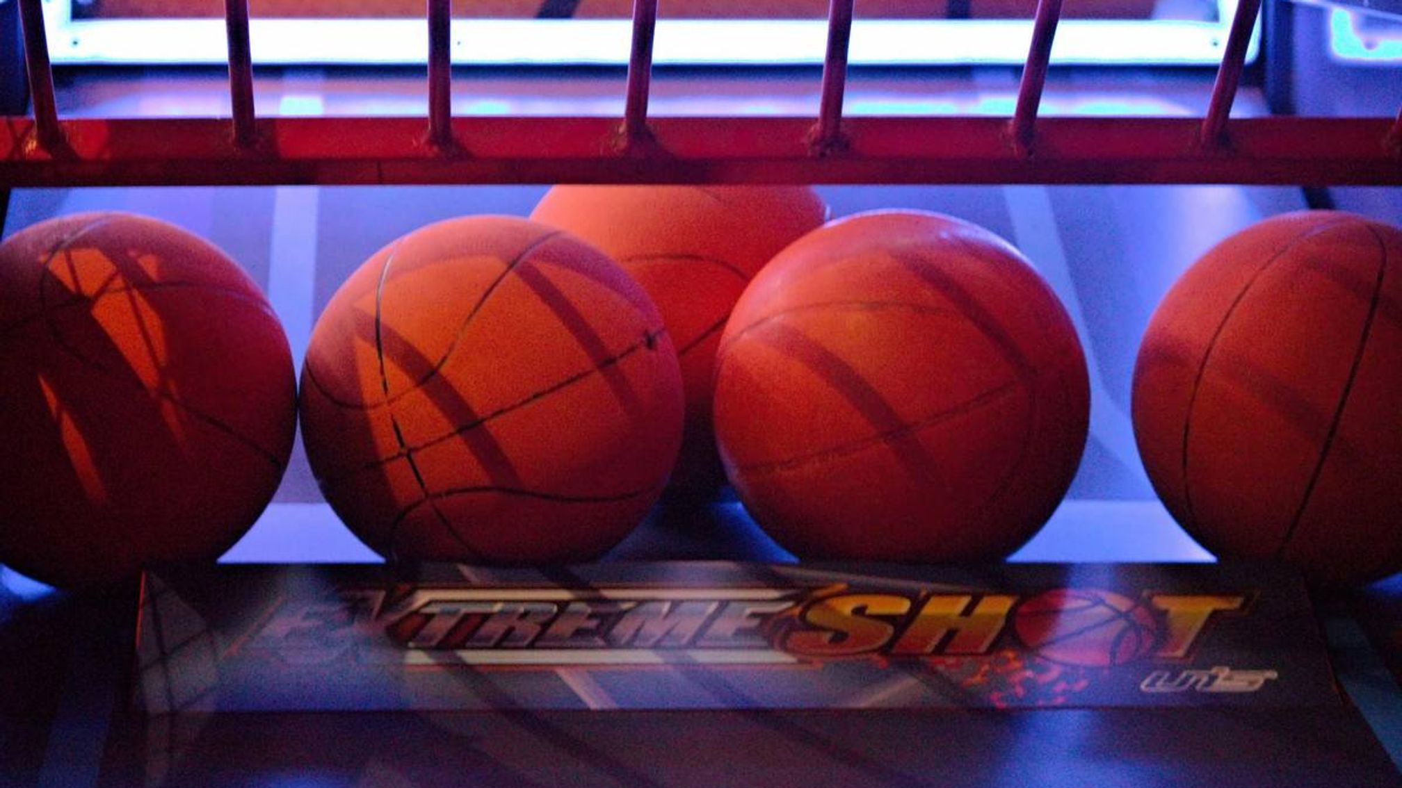 Arcade basketball game inside an entertainment venue, lit in blue and red