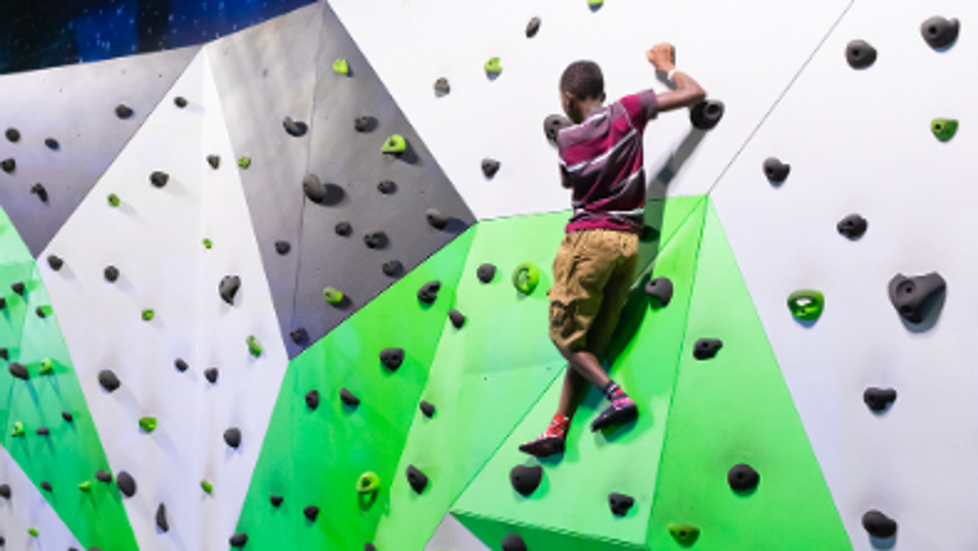 Climber on a colorful indoor bouldering wall