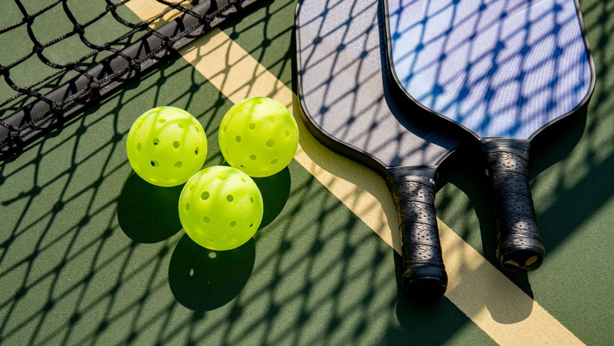 Pickleball paddles and balls on a court — symbolizing the leisure sports boom
