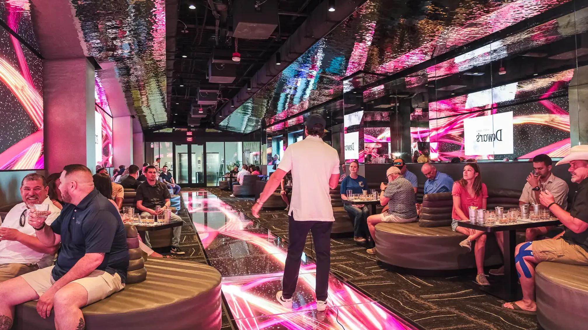 Guests in an immersive LED-lit entertainment venue lounge during a peak-hour event