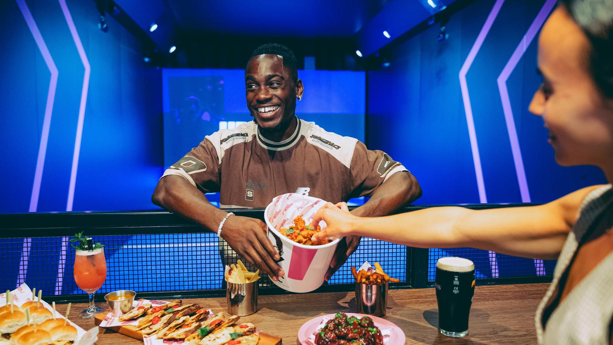 Guests sharing wings, sliders, and cocktails at an eatertainment venue bar