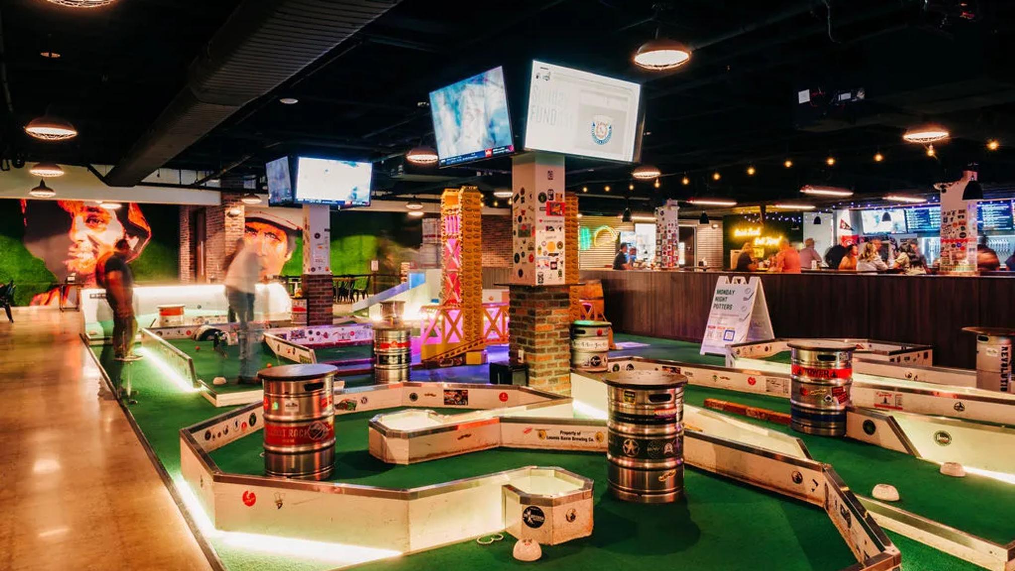 Indoor mini golf venue with beer keg obstacles and a full bar