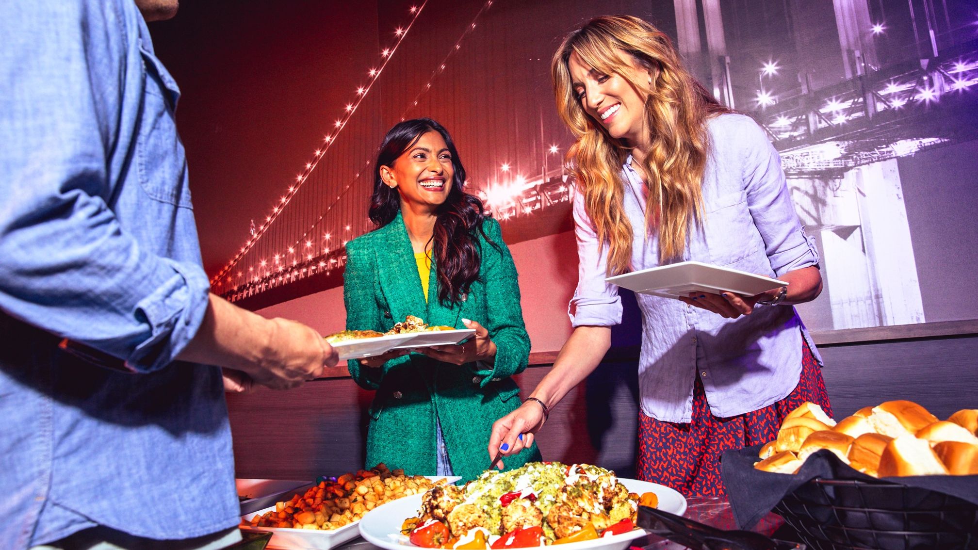 Guests at a corporate event plating food from a buffet at an entertainment venue
