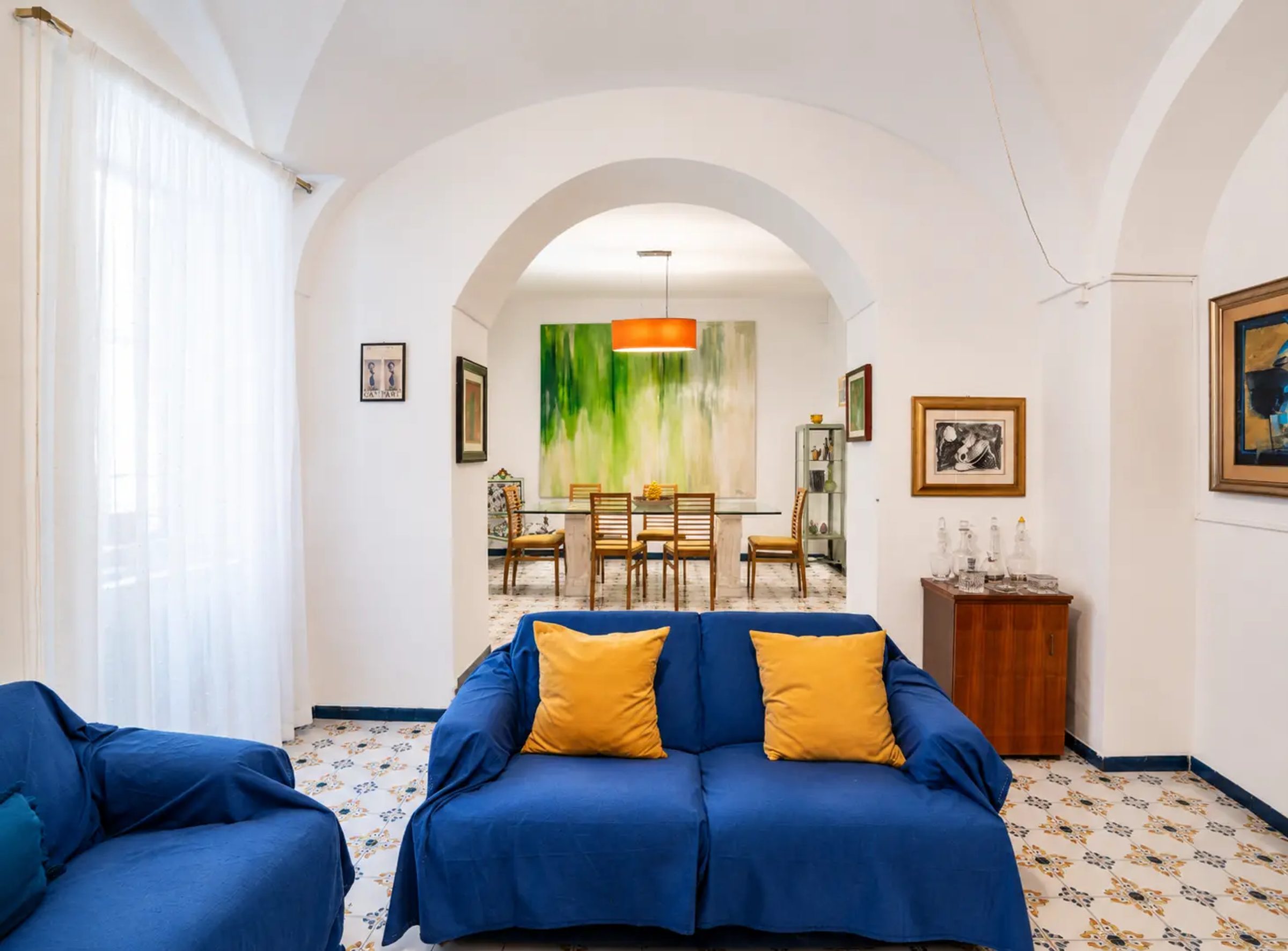 Il soggiorno di un appartamento Le Caraffe, con i divani blu e l'arco che porta alla sala da pranzo