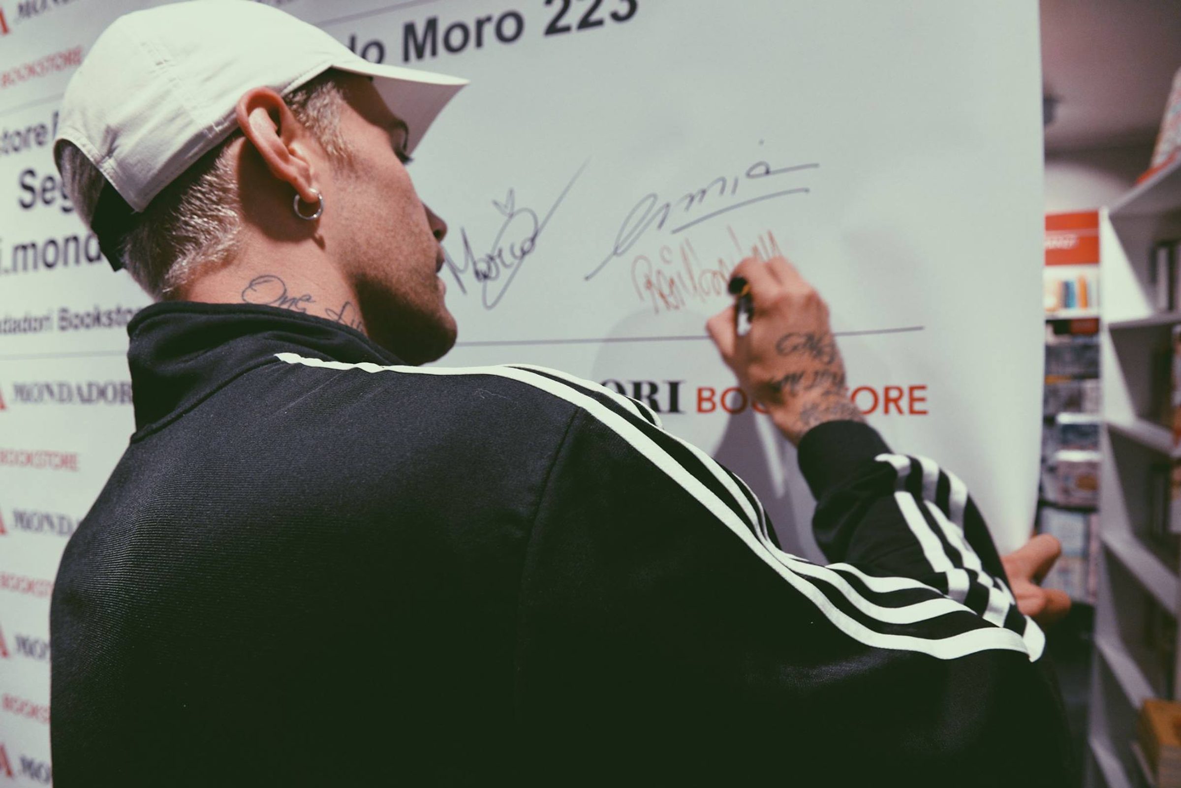 Un artista firma la parete delle dediche del Mondadori Bookstore di via Aldo Moro