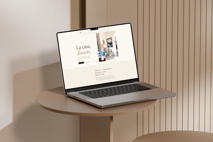 Il sito di Madì Home Design su un portatile appoggiato a un tavolino, con il titolo «La casa, d'autore»