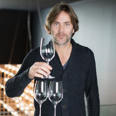 a man is holding two wine glasses in his hands .