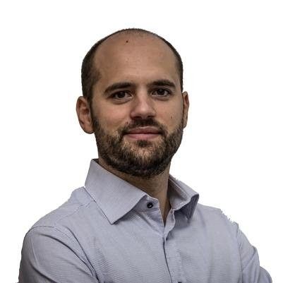 a bald man with a beard is wearing a white shirt and standing with his arms crossed .