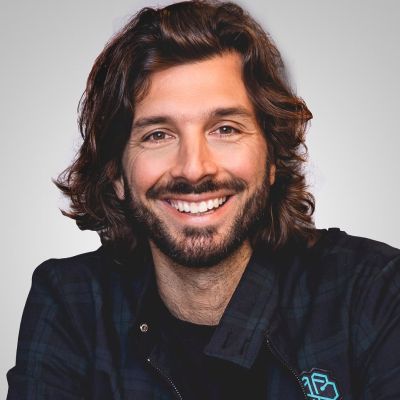 a man with long hair and a beard is smiling for the camera .