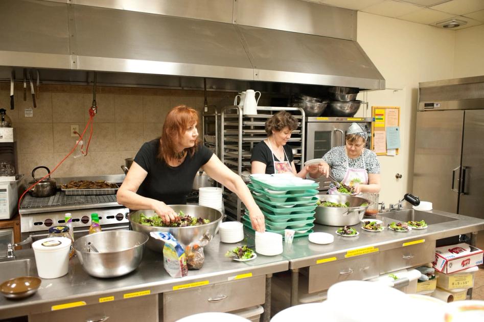 Three women preparing food in a church kitchen