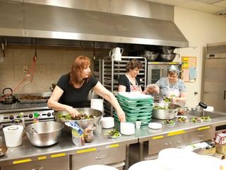 Three women preparing food in a church kitchen