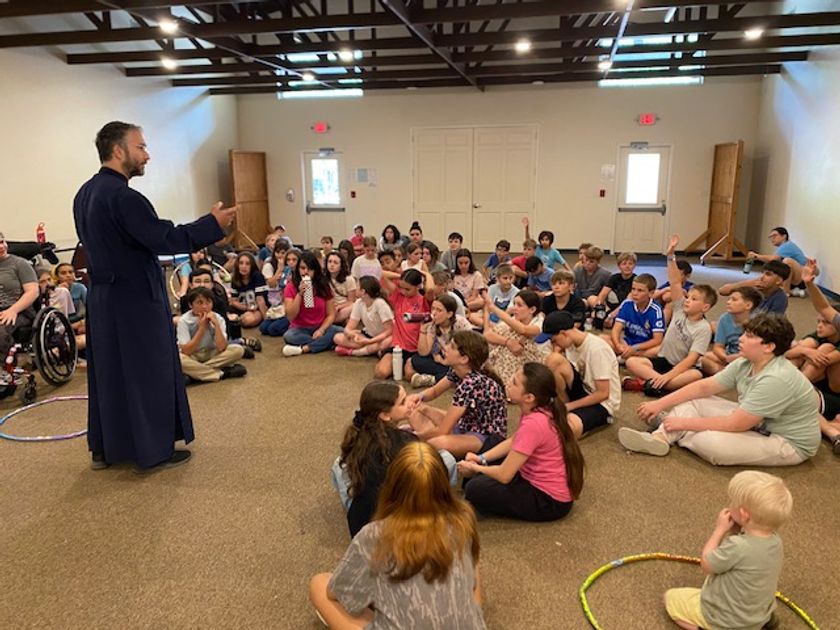 Campers gathered together on the floor listening intently to Father speak.