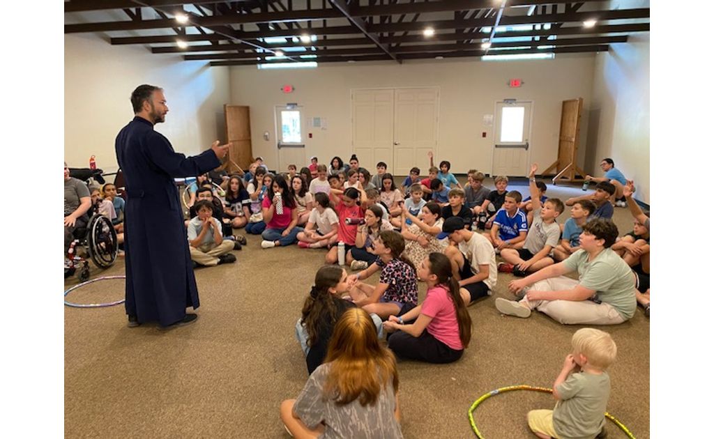 Campers gathered together on the floor listening intently to Father speak.