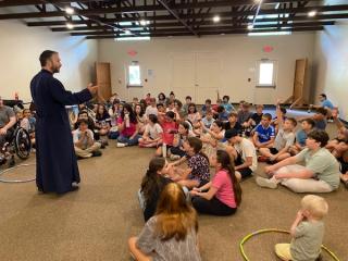 Campers gathered together on the floor listening intently to Father speak.