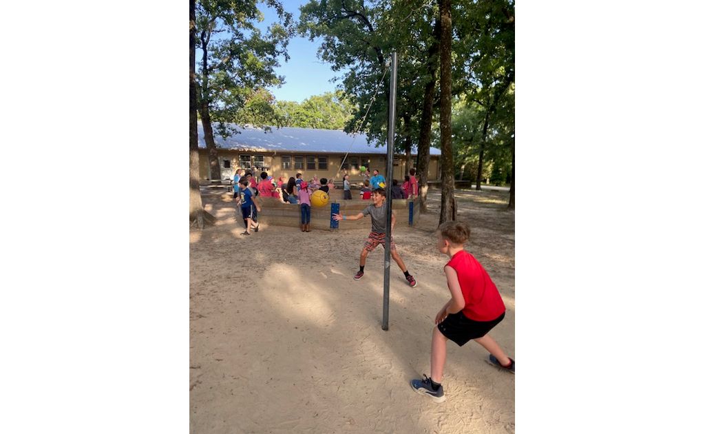 Campers having a blast playing tetherball under the shade of the trees.