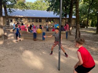Campers having a blast playing tetherball under the shade of the trees.
