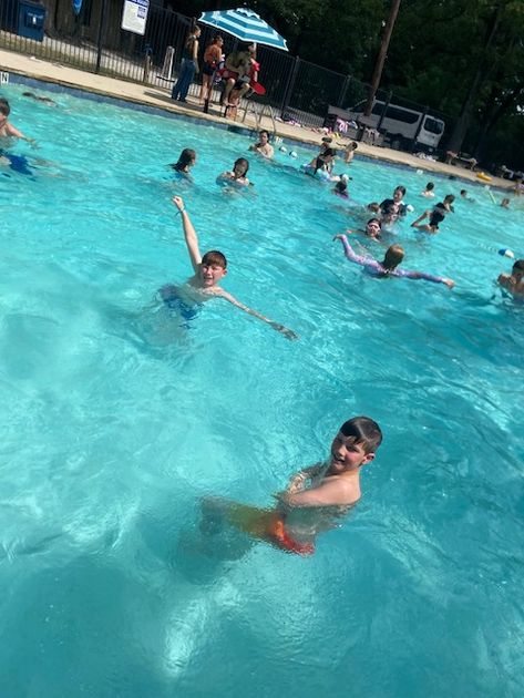 Smiling campers splashing around and cooling off in the outdoor pool.