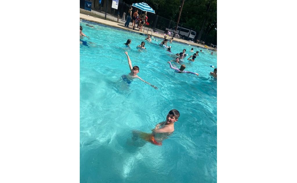 Smiling campers splashing around and cooling off in the outdoor pool.