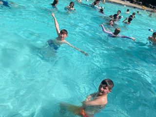 Smiling campers splashing around and cooling off in the outdoor pool.