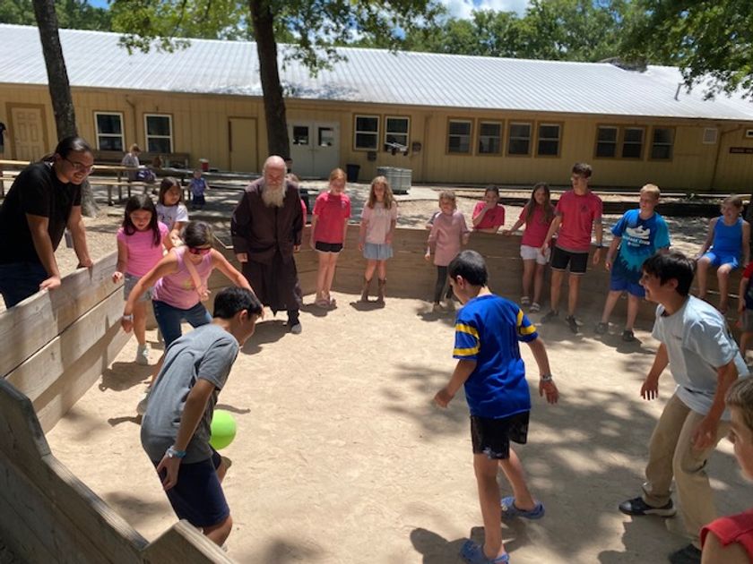 His Grace Bishop Gerasim and a counselor watching the kids play a lively game in the gaga ball pit.