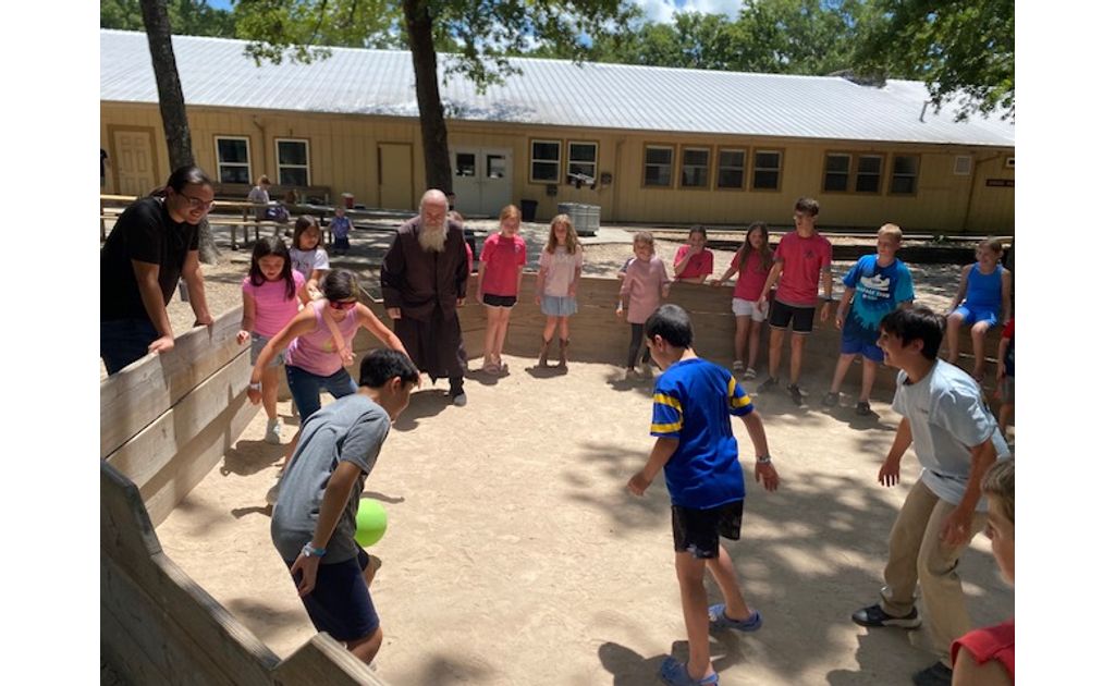 His Grace Bishop Gerasim and a counselor watching the kids play a lively game in the gaga ball pit.