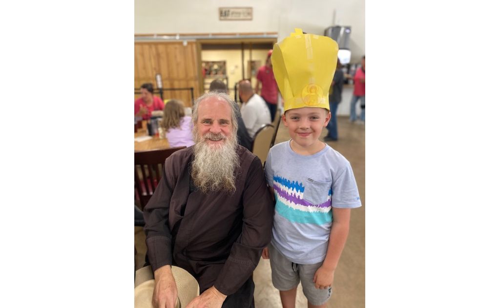 A young camper wearing a homemade paper bishop's crown posing proudly with His Grace Bishop Gerasim