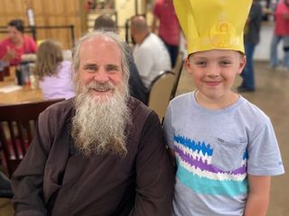 A young camper wearing a homemade paper bishop's crown posing proudly with His Grace Bishop Gerasim