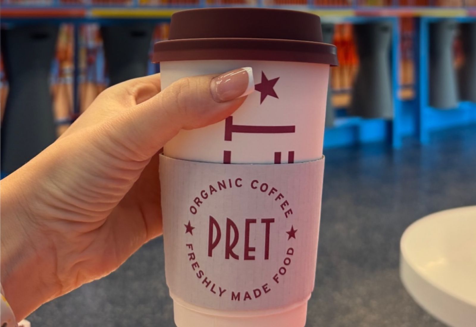 A hand holding a Pret A Manger coffee cup at Trampo Messilah Beach