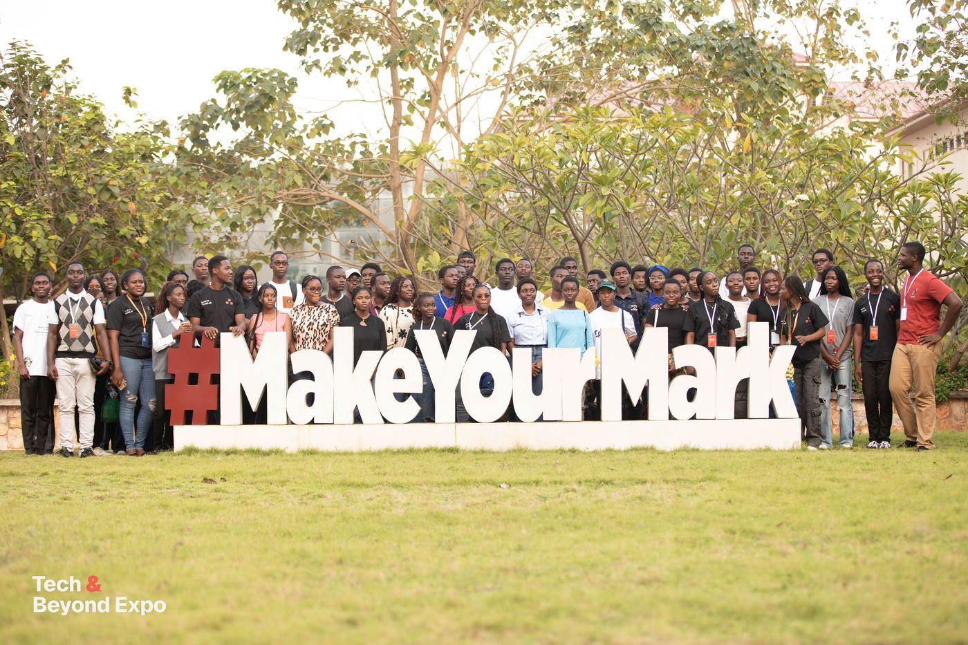 Attendees gathered behind a large #MakeYourMark sign on the lawn