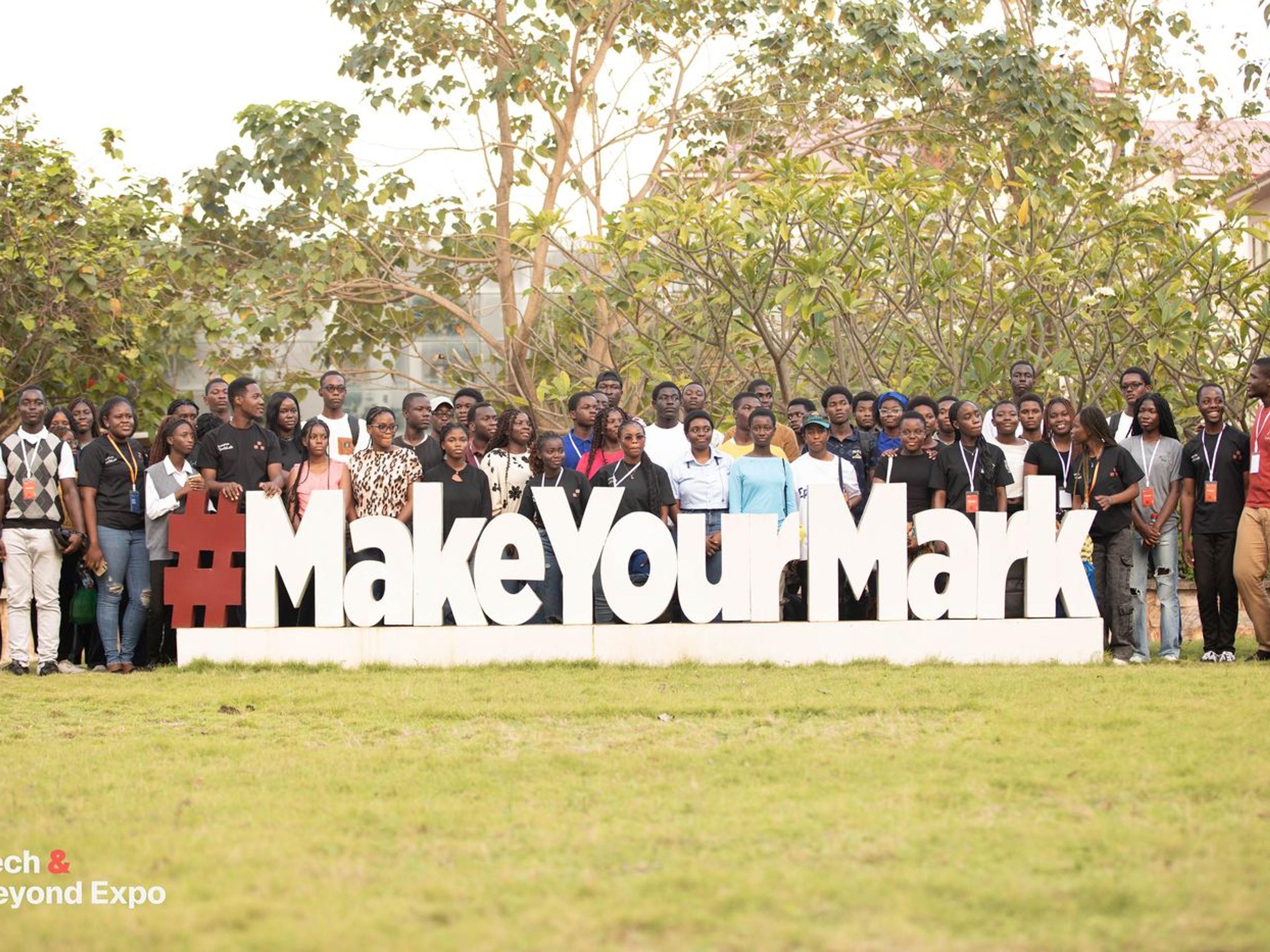 Attendees gathered behind a large #MakeYourMark sign on the lawn