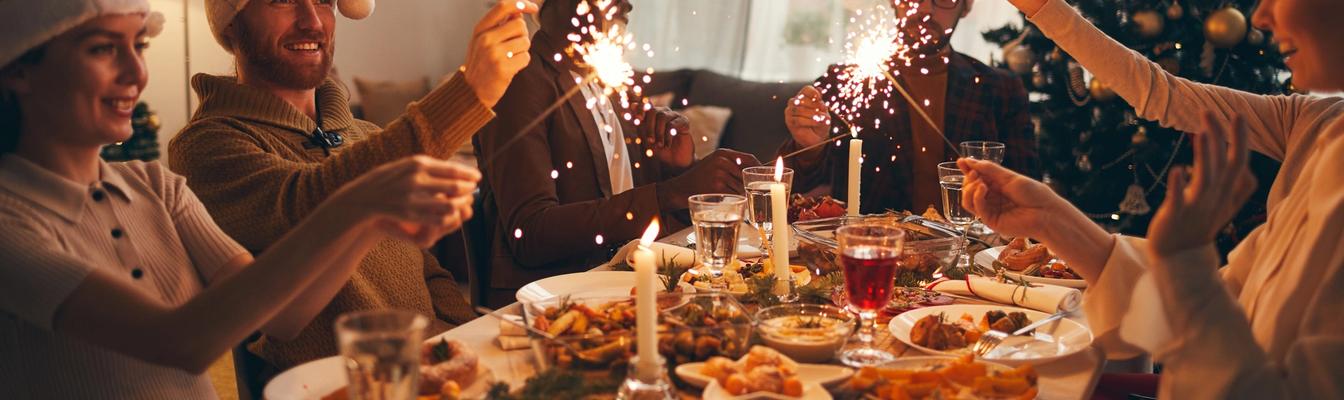 Fem feststemte mennesker med nisselue rundt et juledekket bord 