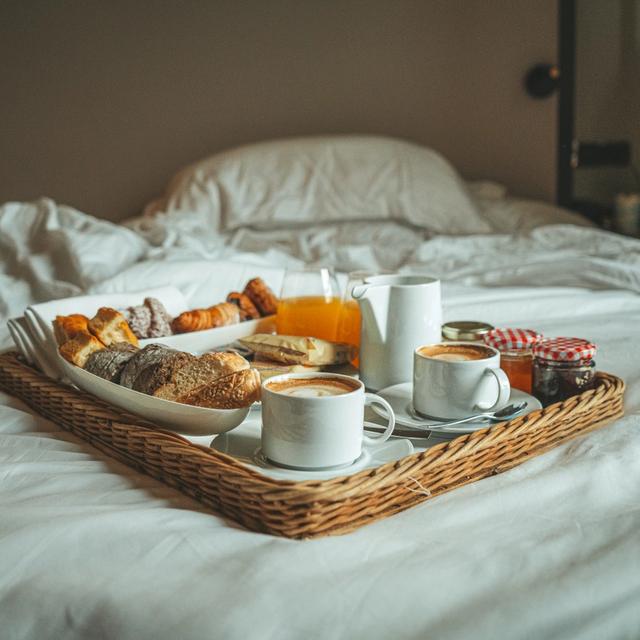 frokostbrett med kaffe på en uoppredd seng