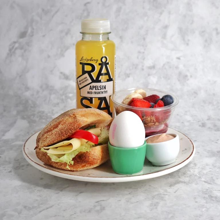 Frukost på en tallrik: En ljus fralla med pålägg, yoghurt med bär, ägg och kaviar samt juice.