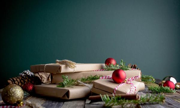 Haug med gaver i gråpapir. Pyntet med granbar, kongler og julekuler i rødt og gull. 