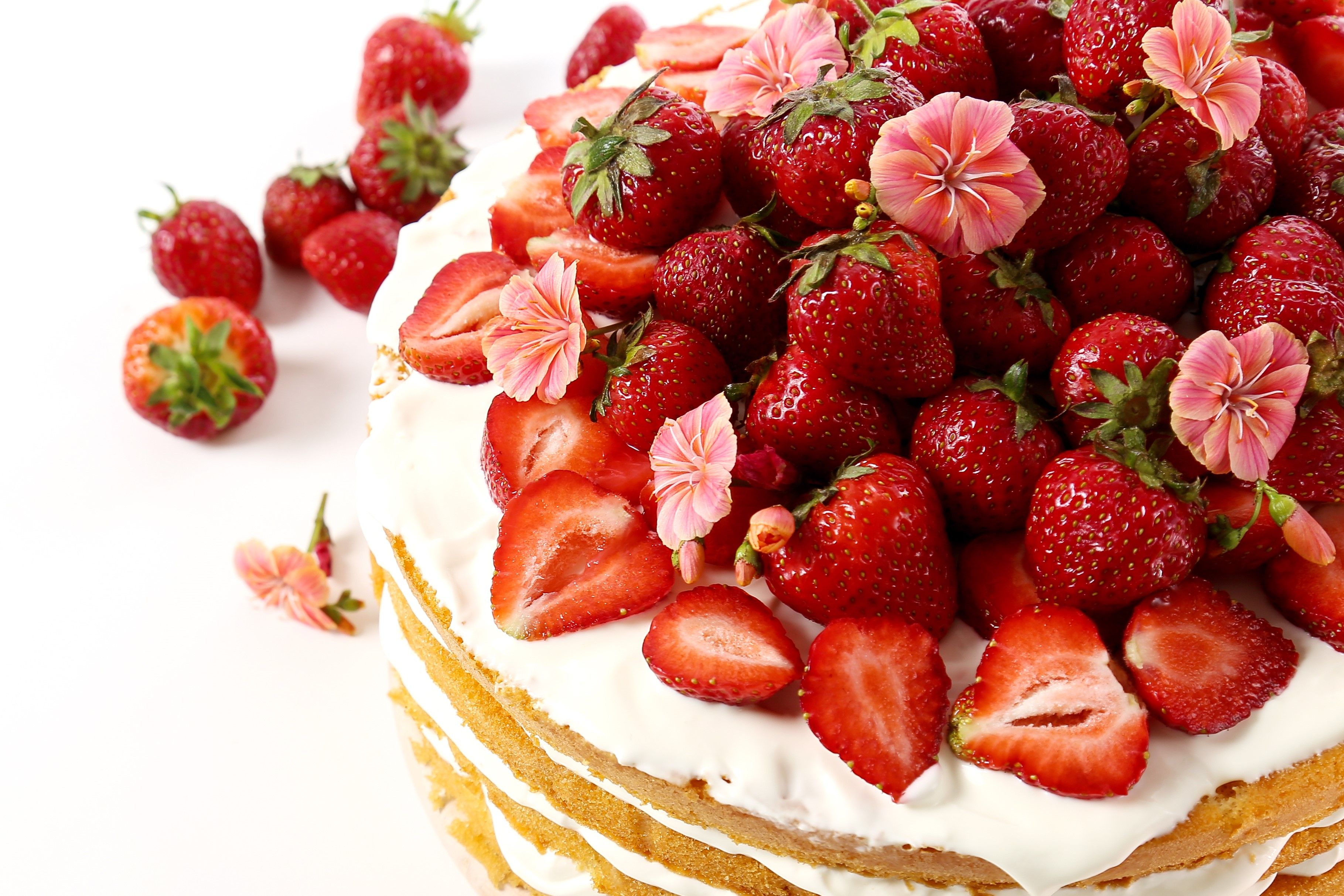 Gräddtårta toppad med jordgubbar och blommor. 