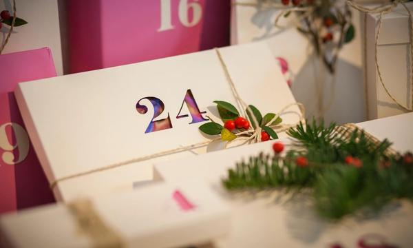 Nummererte gavepakker i rosa og hvitt pyntet med granbar og røde bær 