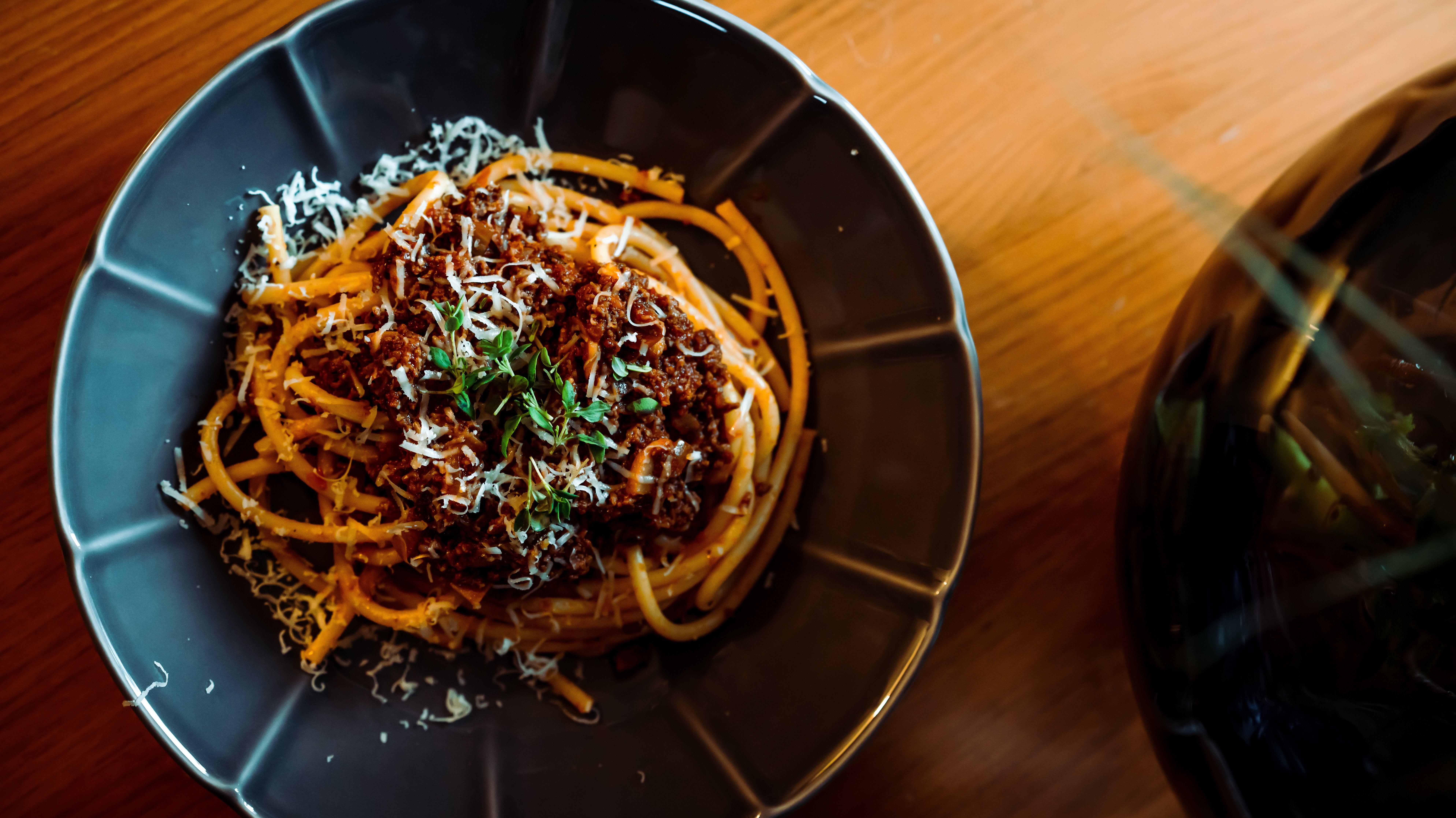 Tallrik med spaghetti och ragù, toppad med parmesan och basilika. 