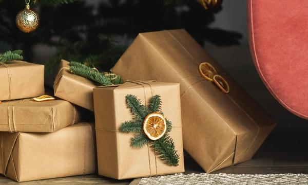 Vackert inslagna paket under en julgran. Pyntade med granris och torkade apelsinskivor. 