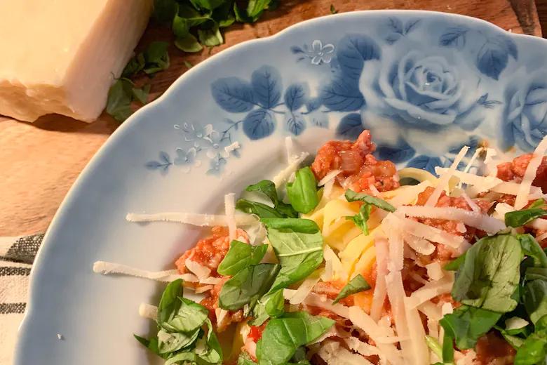 Bilden visar ungefär en tredjedel av en tallrik med salsicciapasta, toppad med parmesan. 