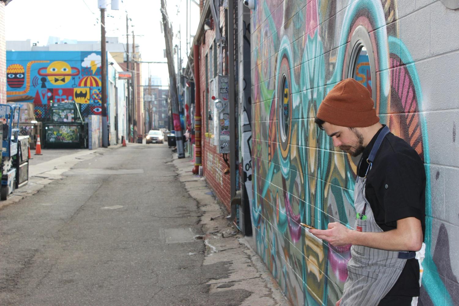 man in black jacket standing beside graffiti wall in riNo Denver during daytime