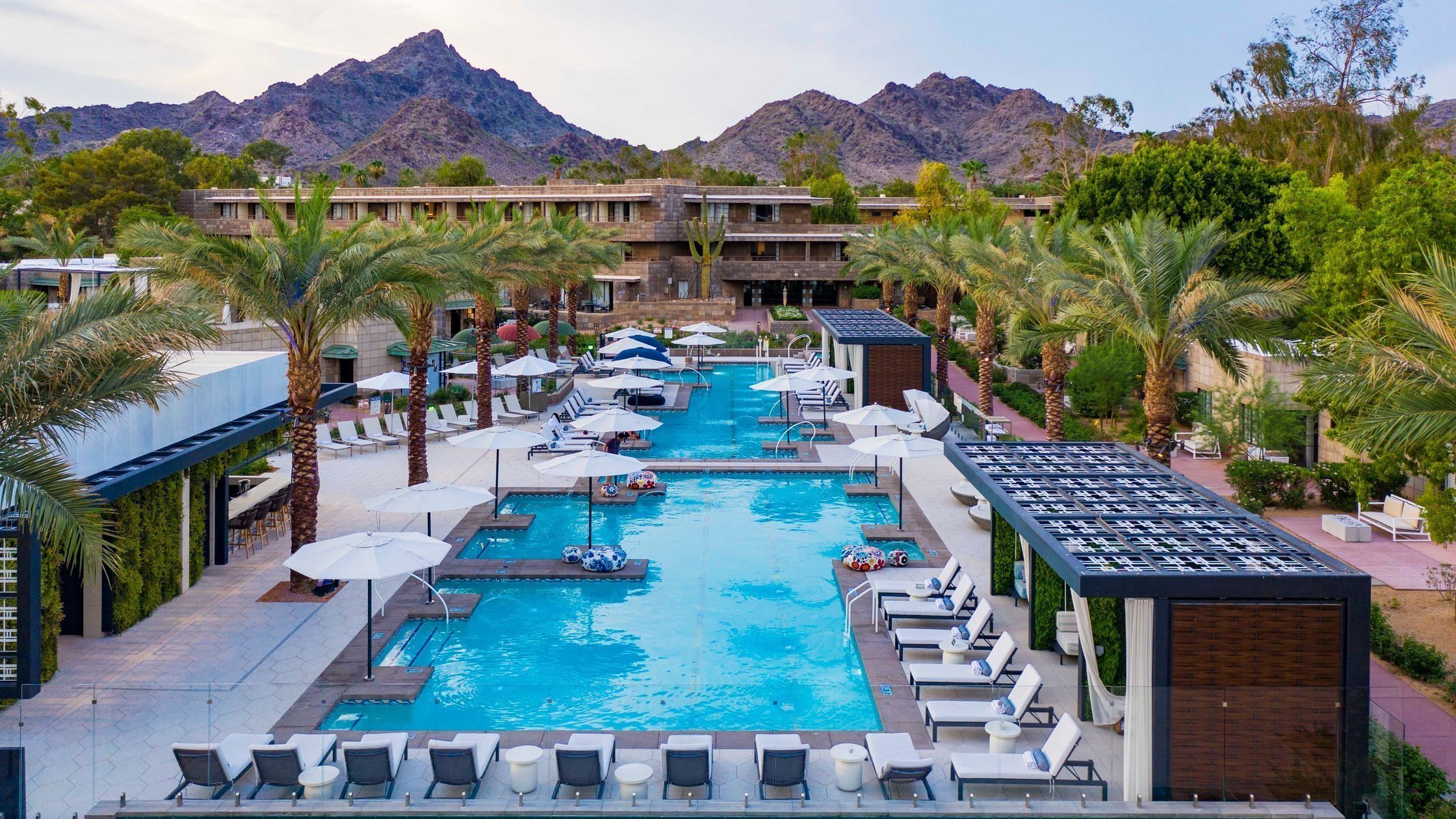 The Arizona Biltmore resort pool framed by palm trees and desert mountains at dusk