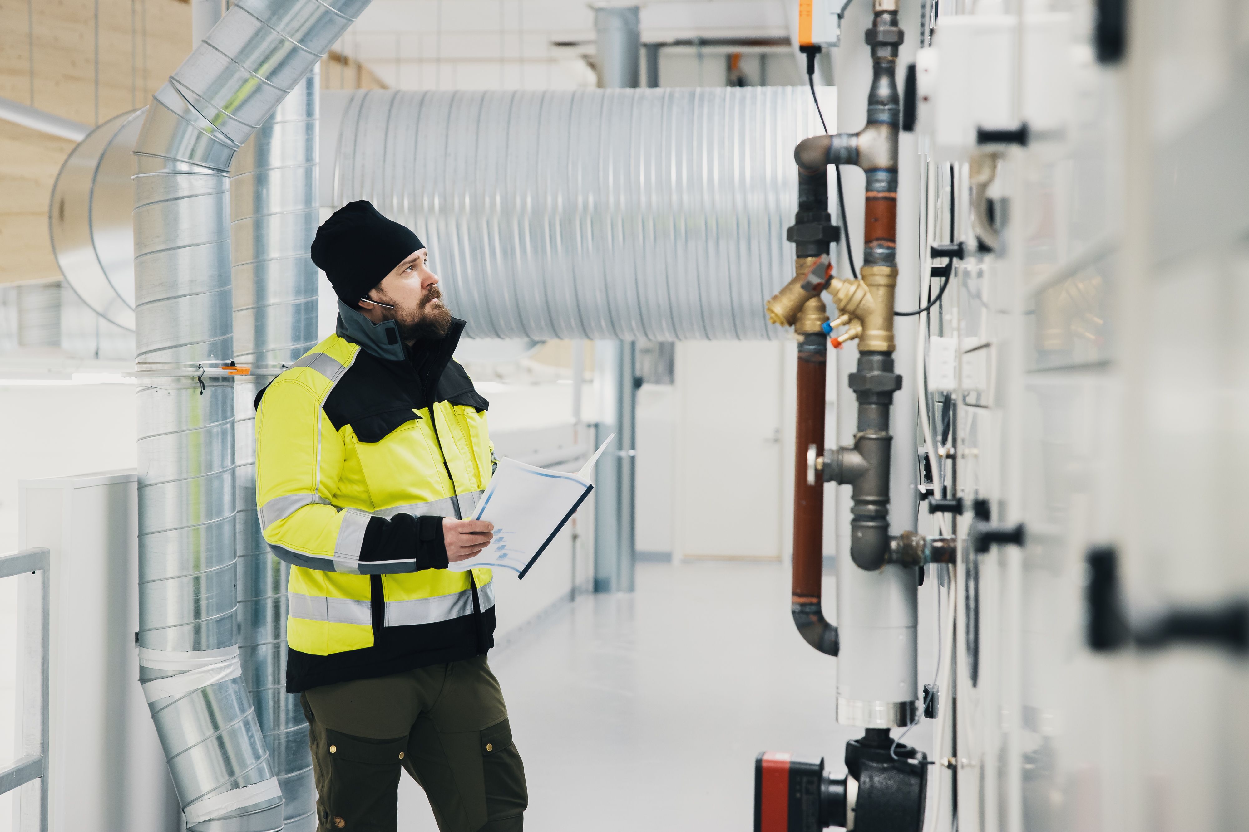 Talotekniikka-ammattilainen tarkastaa ilmanvaihtojärjestelmää - Tammi Kiinteistötekniikka.