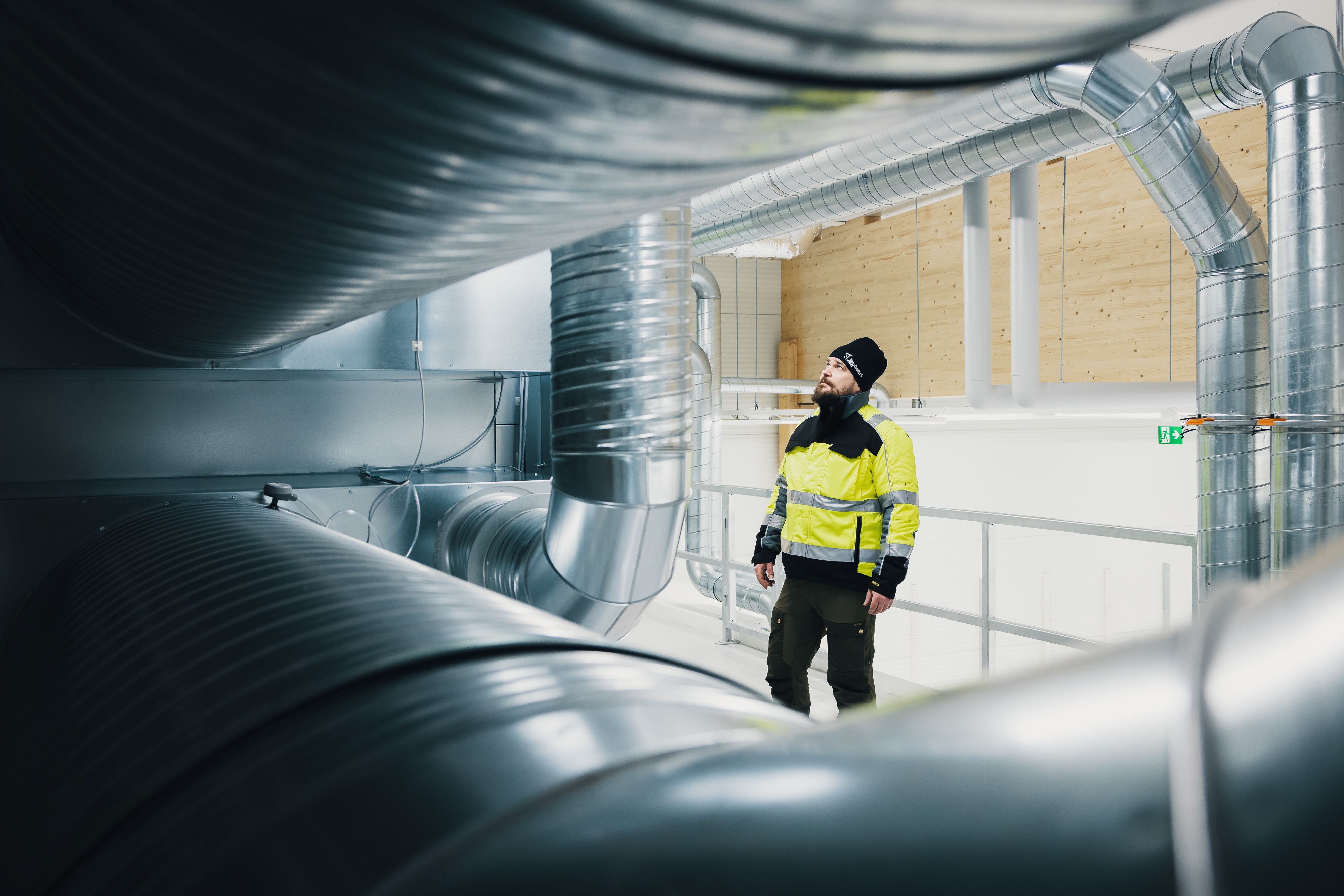 Rakennustekniikan ammattilainen tarkastaa suuria ilmanvaihtokanavia teollisuusrakennuksessa.