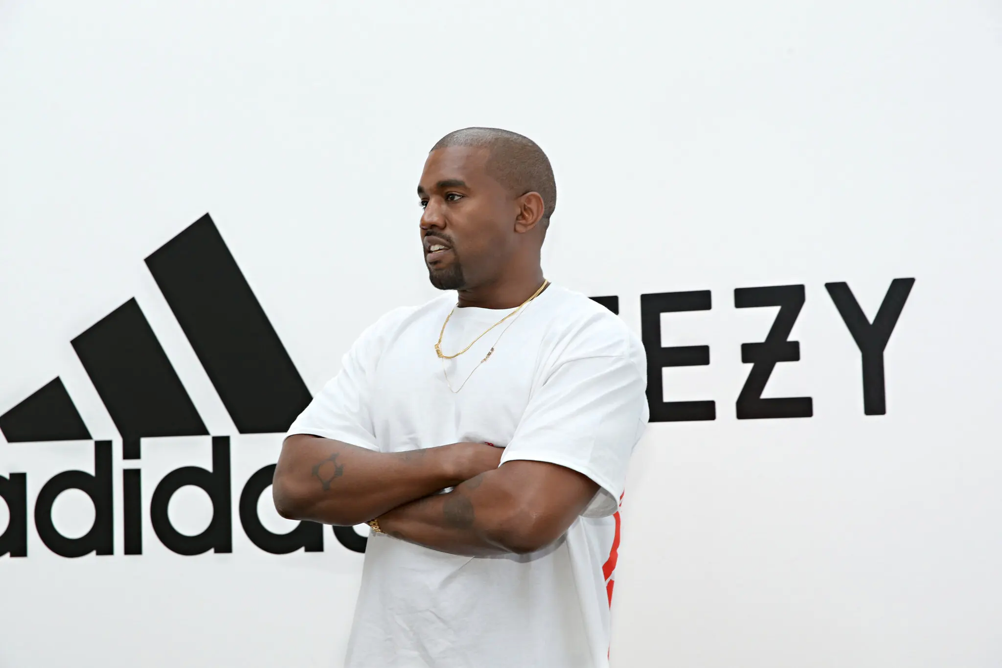 Kanye standing infront of adidas + Yeezy backdrop