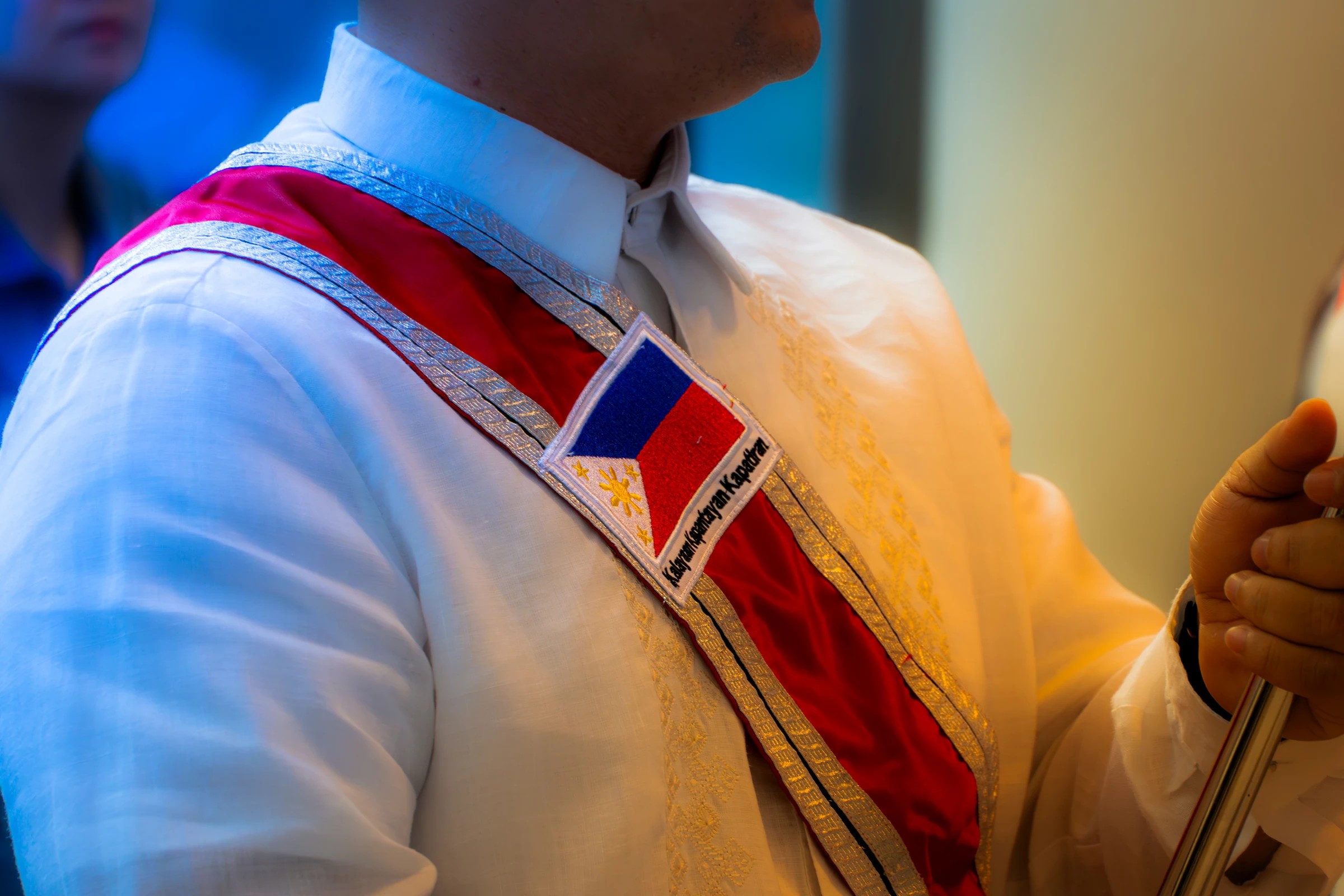 Detail of a formal white outfit with a Philippine sash at PID 2026