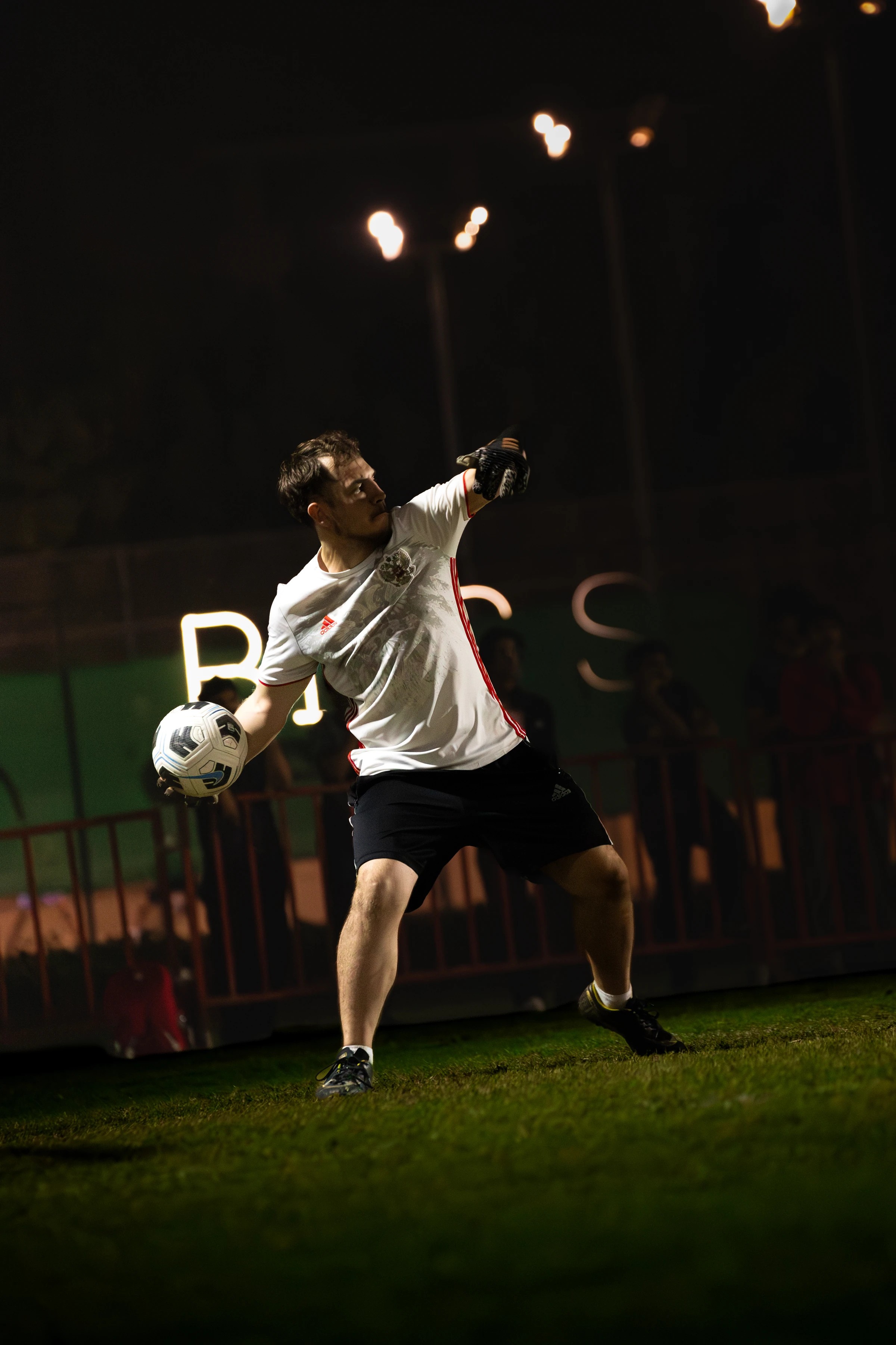 Football player and ball under floodlights