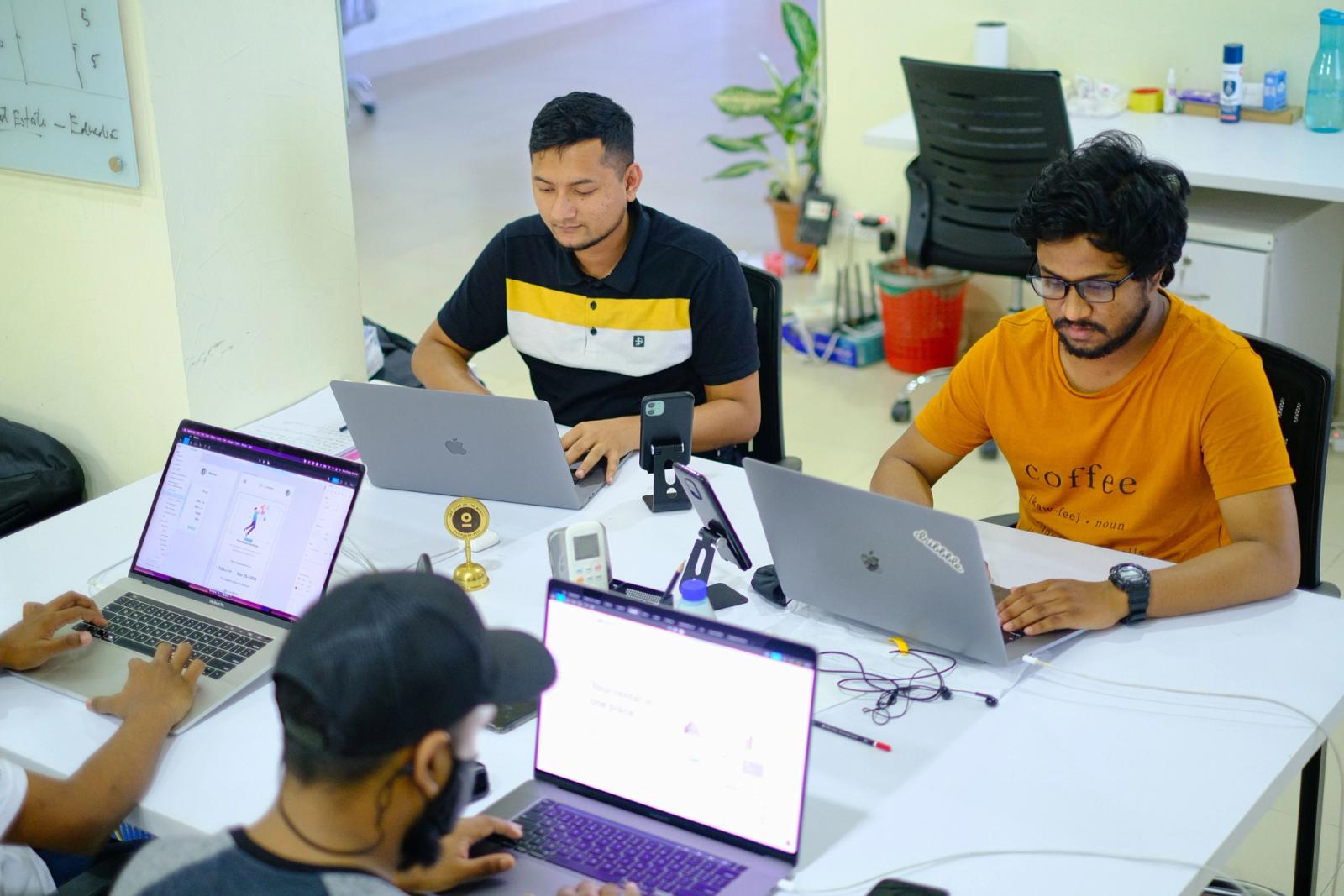 Asian marketing team collaborating with laptops in a modern office