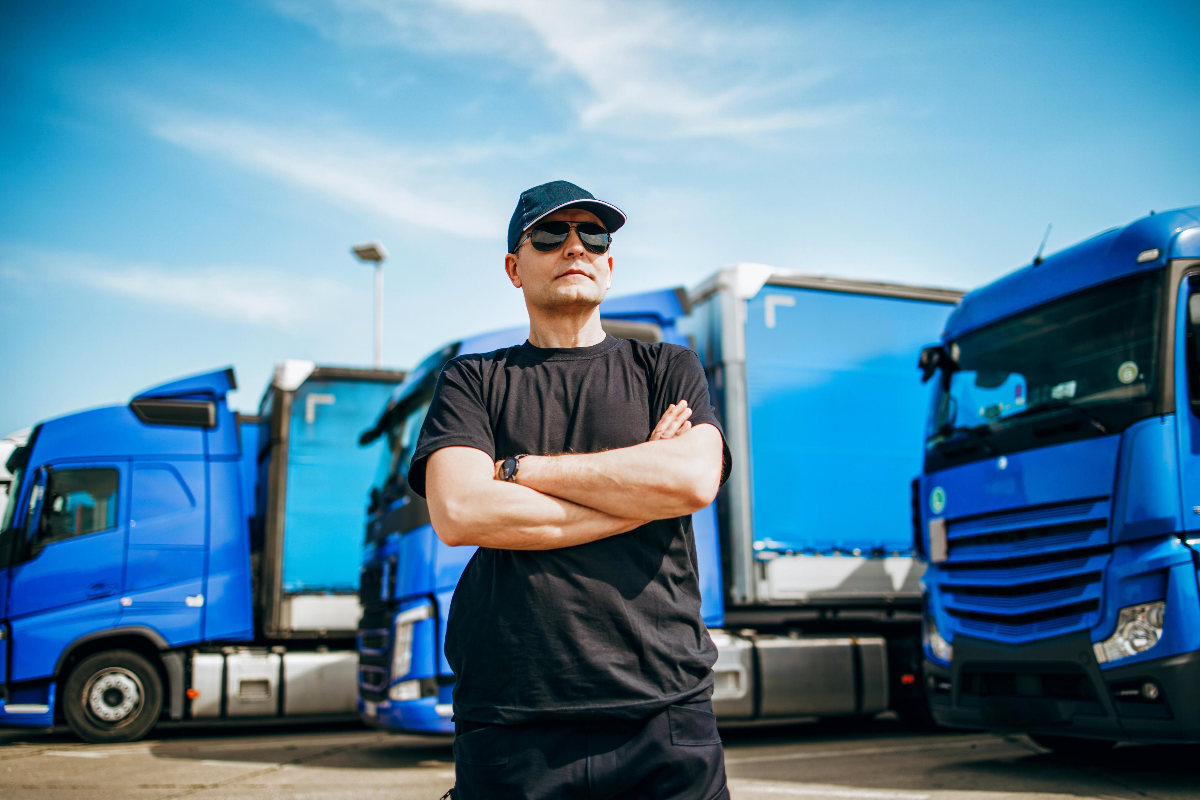 A driver standing by a fleet of trucks supported by quality slide bar parts
